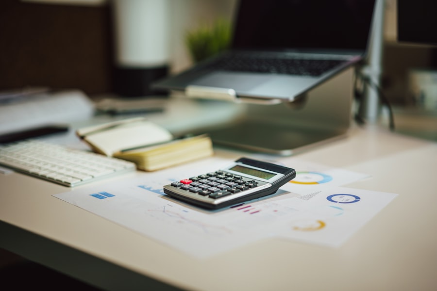 A calculator and laptop on a work table