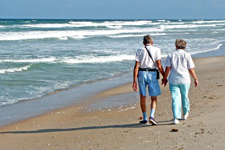 A retired couple walking hand in hand along the beach